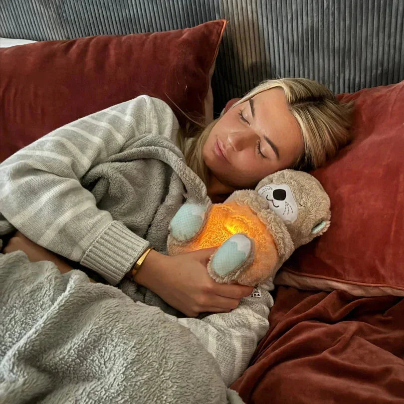 Frau kuschelt mit leuchtendem Otter-Kuscheltier im Bett, Morivar innovative Accessoires