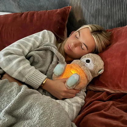 Frau kuschelt mit leuchtendem Otter-Kuscheltier im Bett, Morivar innovative Accessoires